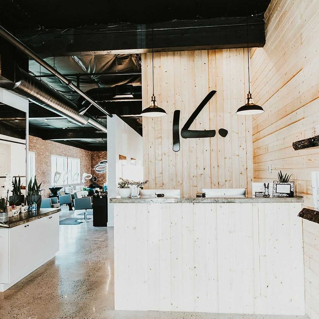 Front desk with the 'K' logo on the wall. Dryer chairs visible in the background