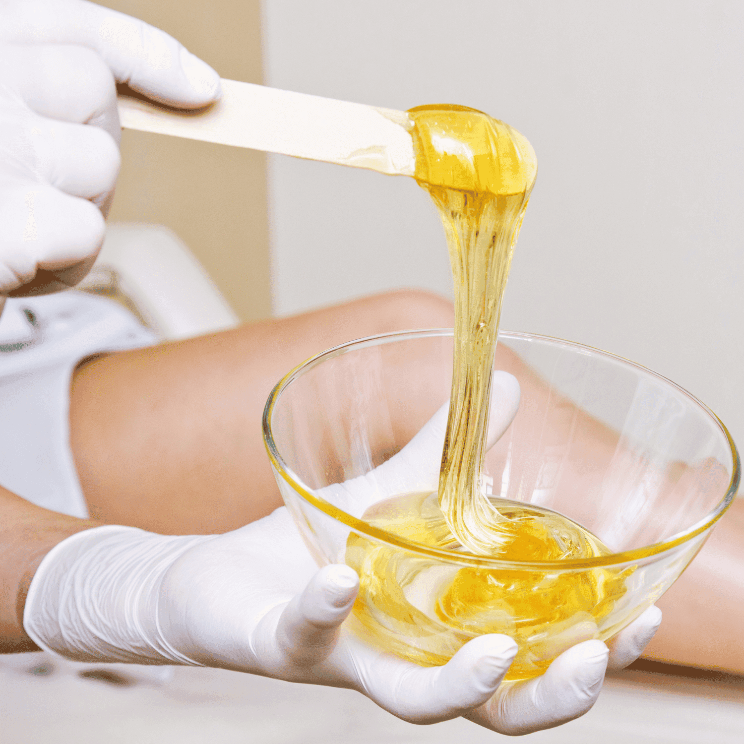 Waxing preparation with spatula and bowl of warm wax in a spa setting.